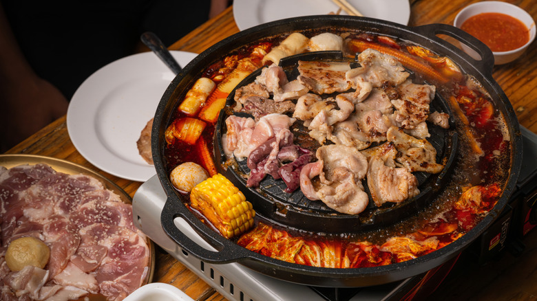 A BBQ grill with pieces of meat cooking on top