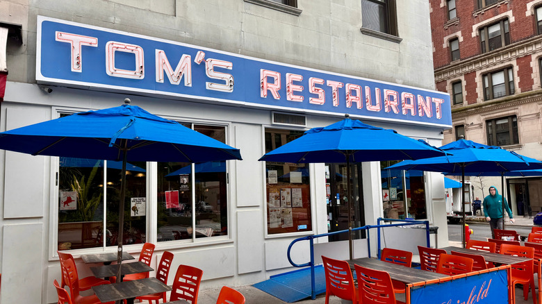 The outside of the restaurant featured in Seinfeld has a big sign that reads "Tom's," as well as patio tables with umbrellas