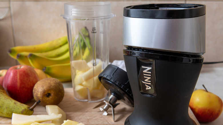 Ninja juicer on a counter surrounded by fruit.