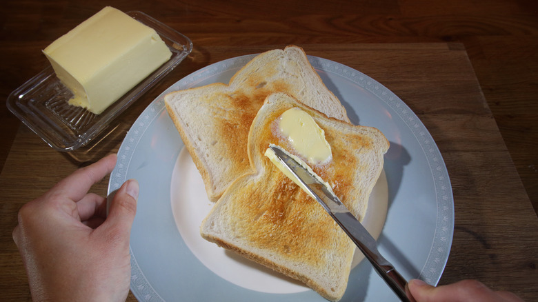 Person spreading soft butter onto toast