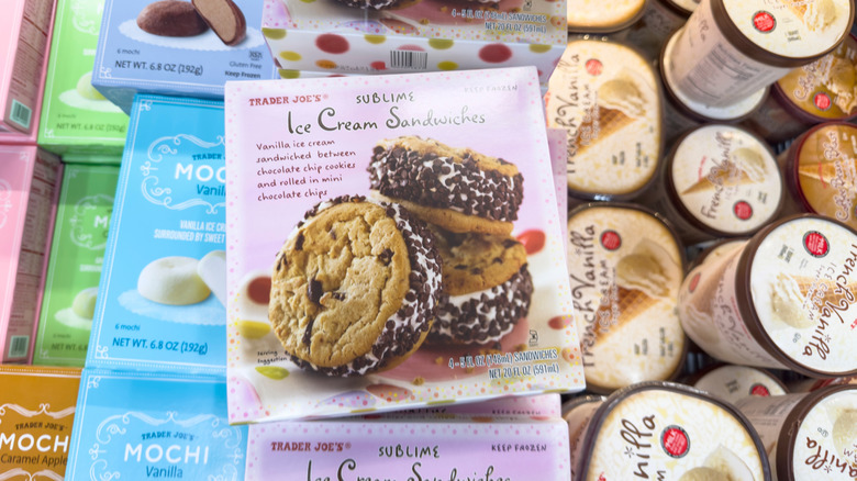 Various Trader Joe's ice cream products sit in a freezer, including cartons of French Vanilla and Coffee Bean Blast, boxes of chocolate chip cookie ice cream sandwiches, and boxes of chocolate and vanilla mochi.