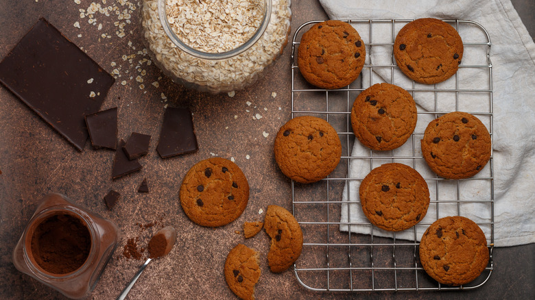 Homemade cookies resting on a wire rack with ingredients arranged in the frame.