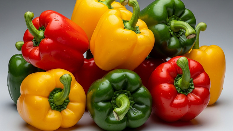Red, yellow, and green bell peppers are stacked together.