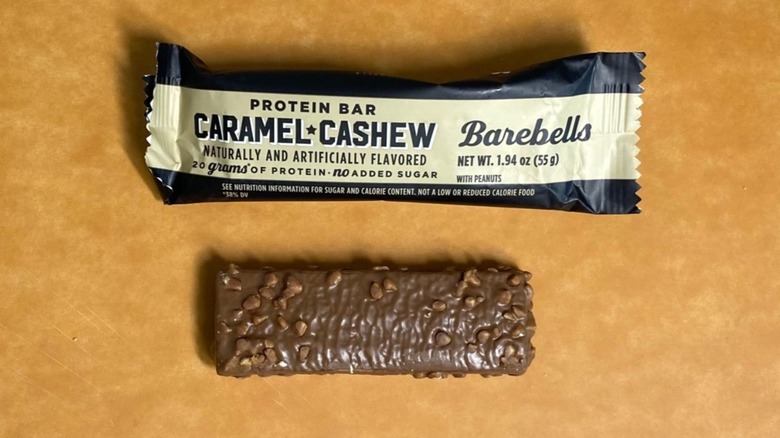 a Caramel Cashew Barebells protein bar beside its packaging