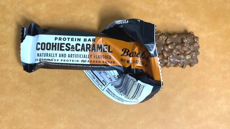 a Cookies and Caramel Barebells protein bar peeking out of its packaging