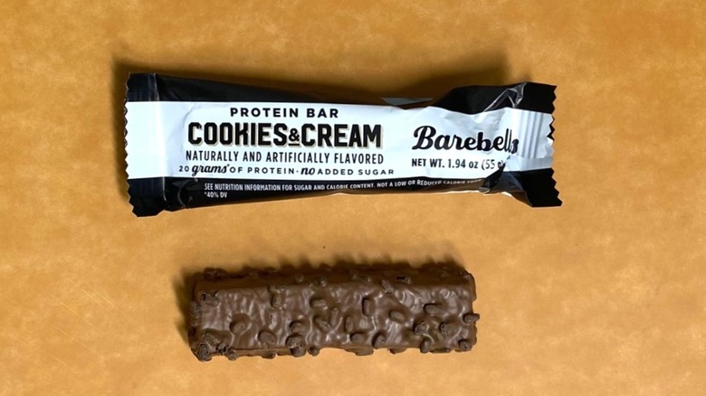 a Cookies and Cream Barebells protein bar beside its packaging