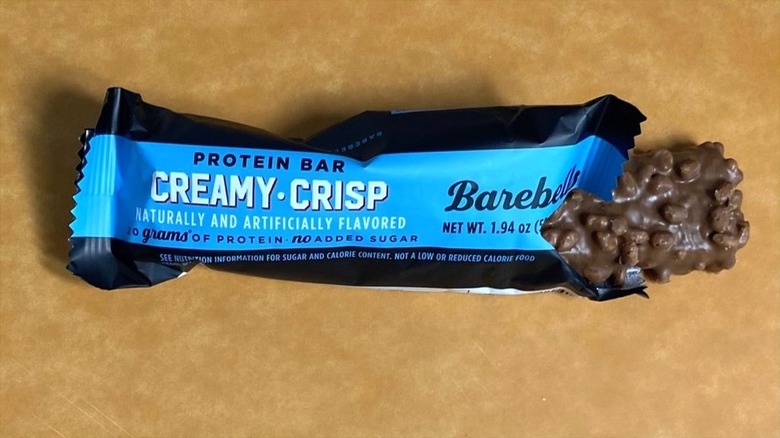 a Creamy Crisp Barebells protein bar peeking out of its packaging