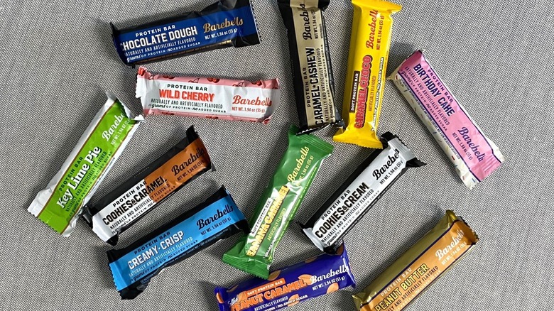 12 Barebells protein bar flavors scattered on a gray table