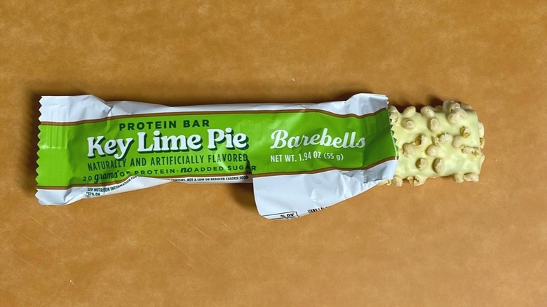 a Key Lime Pie Barebells protein bar peeking out of its packaging