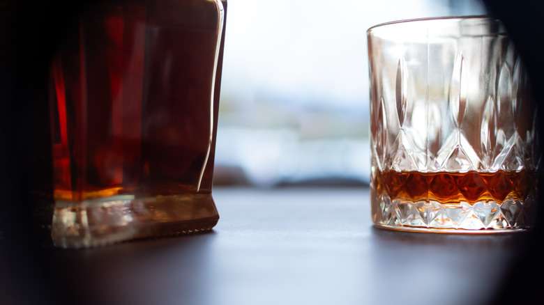 Jack Daniel's whiskey bottle with a small amount poured into a glass for tasting