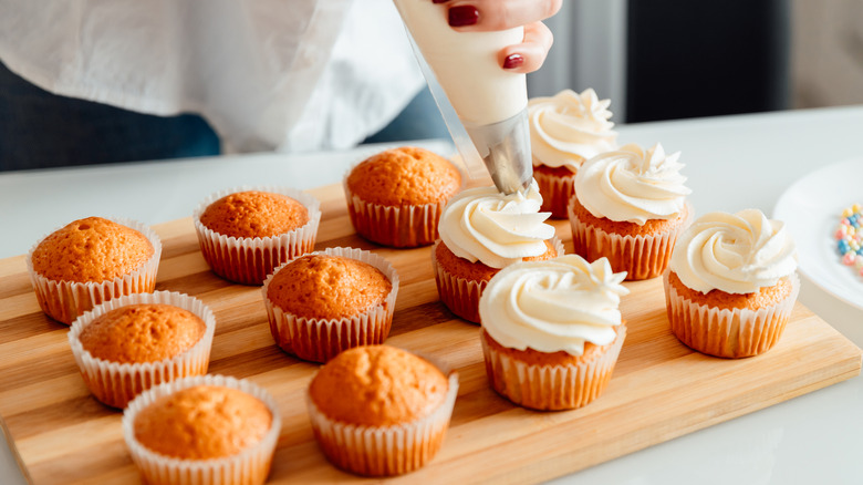 Frosting cupcakes on cutting board