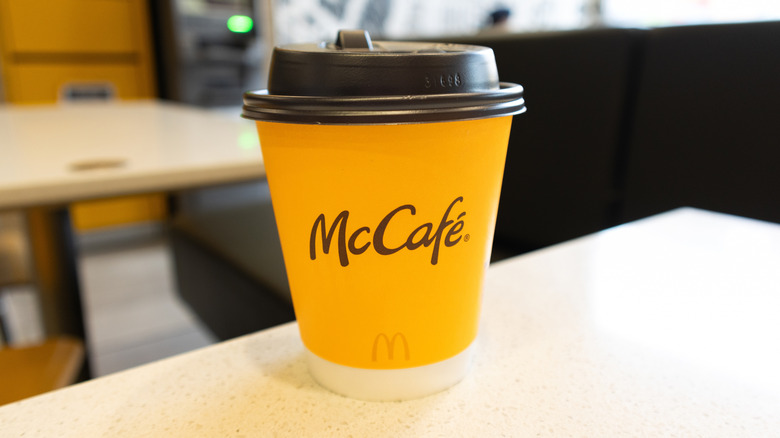 A cup of coffee rest on a table in a McDonald's restaurant