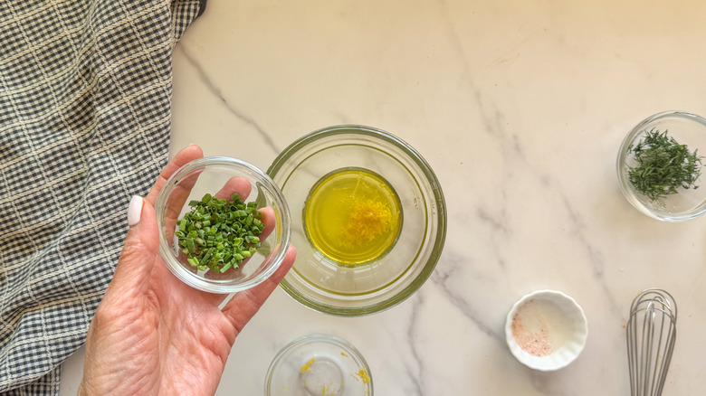 hand adding chives to bowl