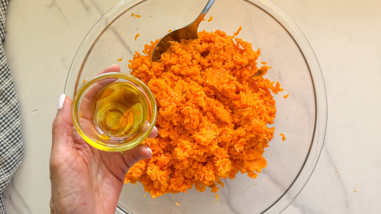 hand adding olive oil to bowl