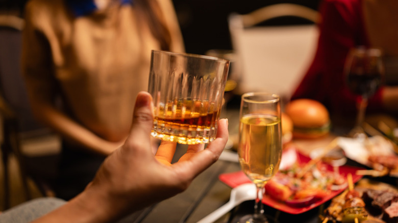 A person holding a glass of whiskey in a bar.
