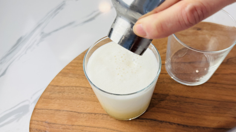 Pouring whiskey sour with egg white foam