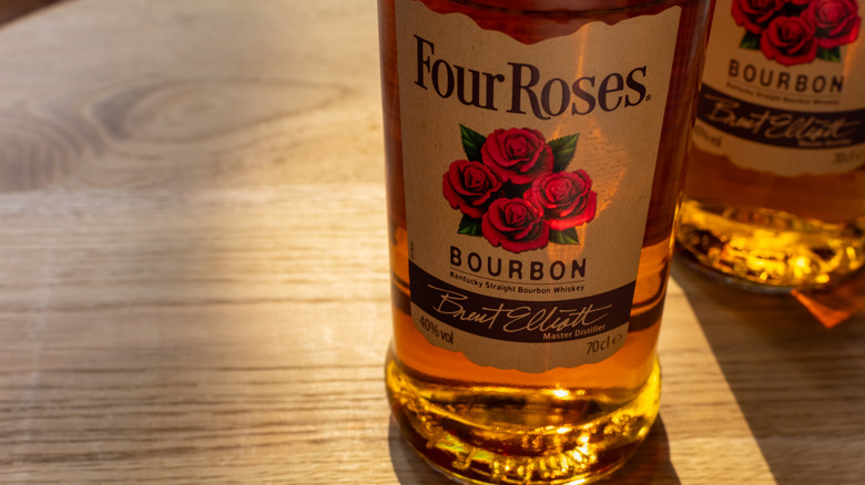 A bottle of Four Roses Bourbon Whiskey sits atop a wooden table