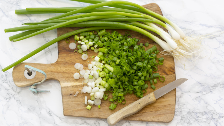 Daun bawang utuh dan dipotong di papan