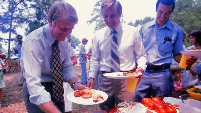Jimmy Carter and Walter Mondale serve themselves food at a reunion for Rosalind Carter's family