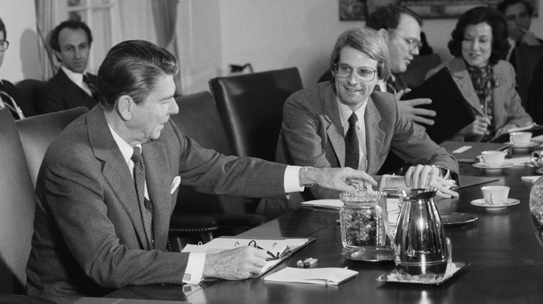 Ronald Reagan passes a jar of jellybeans to his budget director during a meeting
