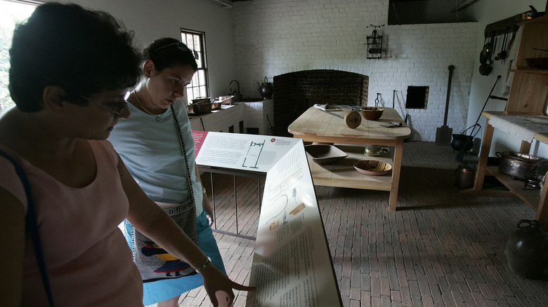 Two women tour the kitchen at Monticello and look at signs with historical information