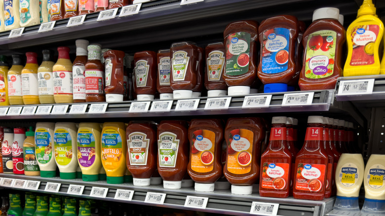 A store shelf stocked with tomato ketchup and other condiments