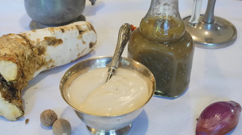 Servings of white ketchup in a metal sauce bowl and a glass bottle