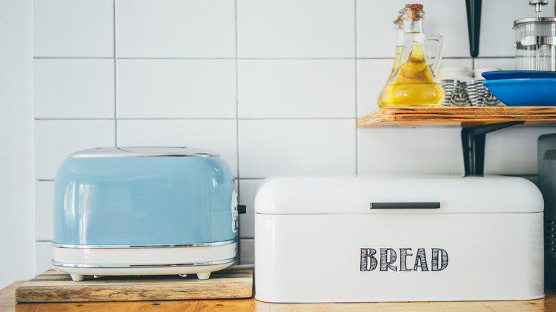 A blue toaster next to a white bread box