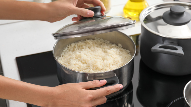 Person cooking white rice in a pot on the stovetop.