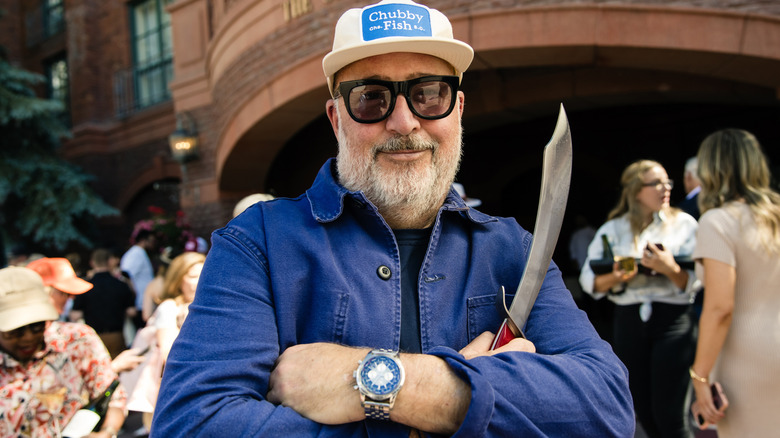 Andrew Zimmern smiling and holding a sword