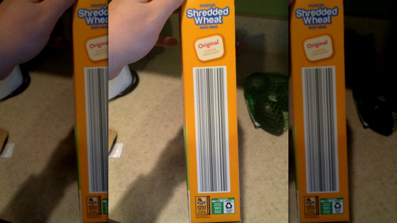 Hand holding an Aldi Shredded Wheat cereal box with a long barcode