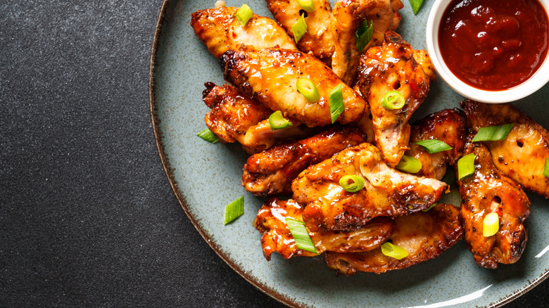 A plate of chicken wings with barbecue sauce in the center.