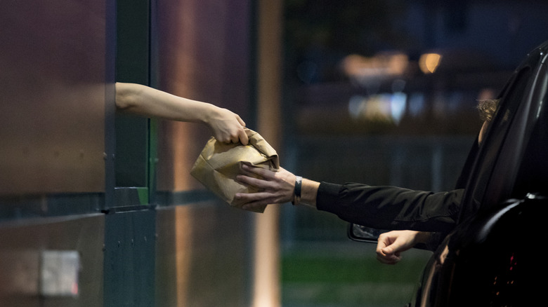Person receiving food at late-night drive-thru window.