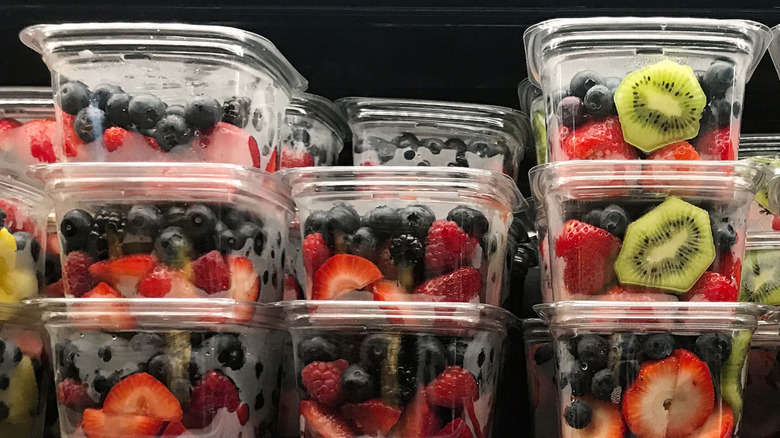 Containers of sliced fruit on a grocery store shelf