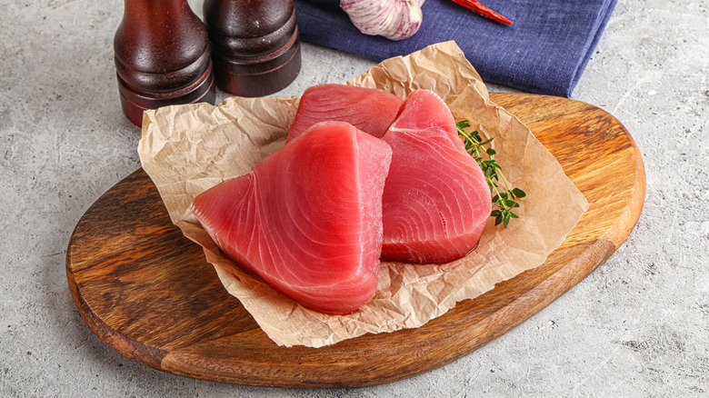Uncooked tuna steaks on a wooden tray.