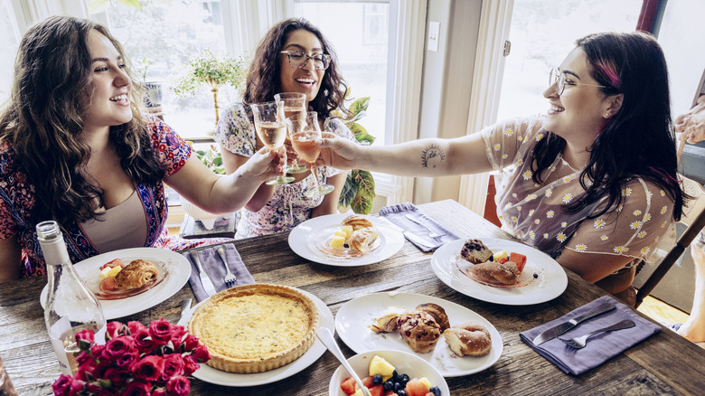 three women toasting with champagne over brunch