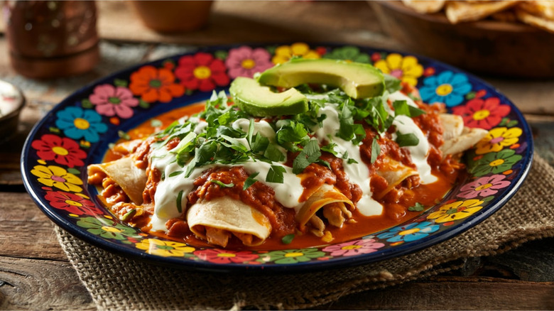 Plate of enchiladas with two sauces and sliced avocado