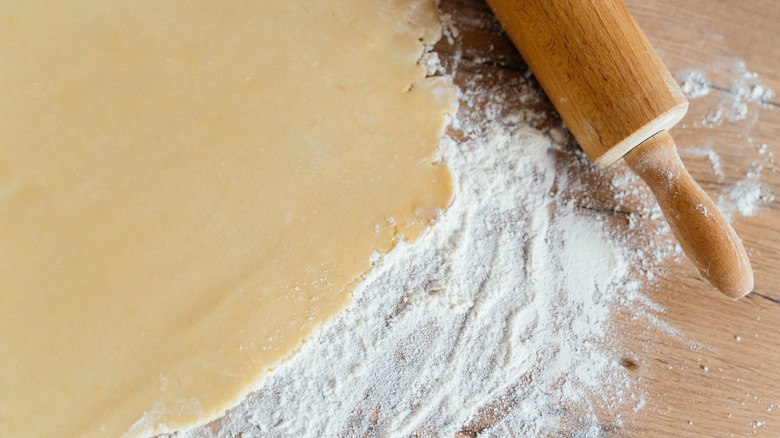 Photo of dough rolled out with flour on the board with a rolling pin