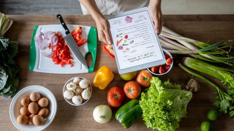 A person cooking with recipe pulled up on tablet