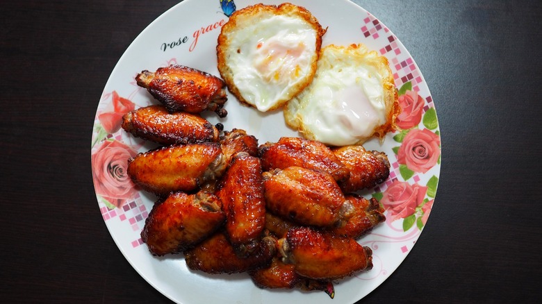 a plate chicken wings with two fried eggs