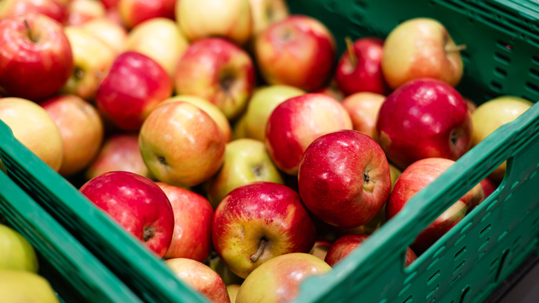 Red and yellow apples in a green basket