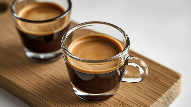 An illustrative image showing two espresso glasses on a wooden board