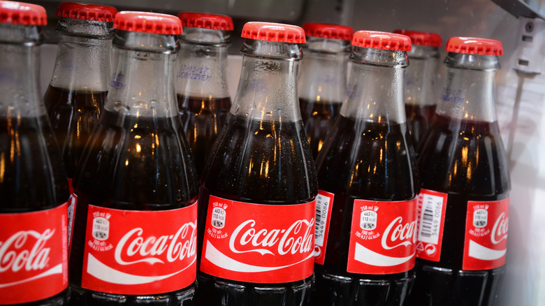 Bottles of Coca-Cola on a shelf.