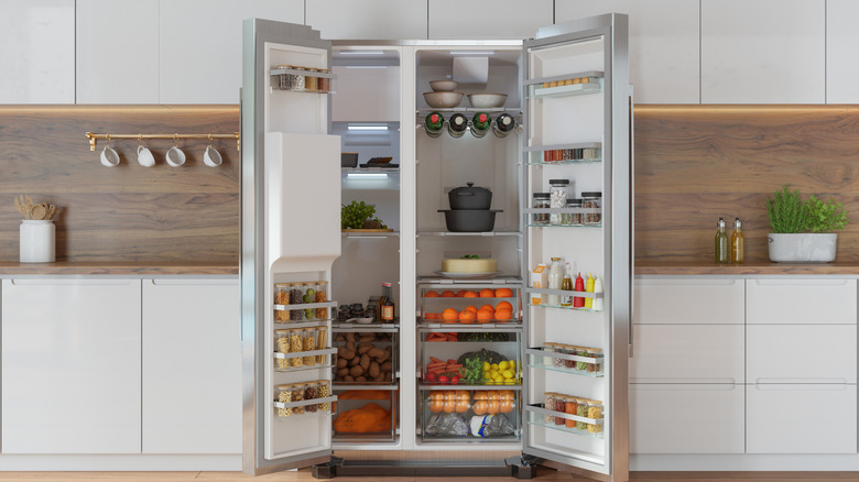 An open refrigerator in a kitchen, filled with food and drinks