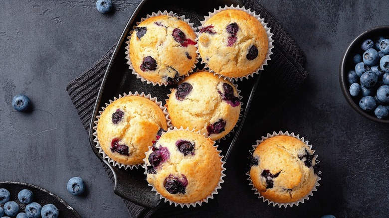 Homemade blueberry muffins in a rectangular cast iron baking dish over a black dish towel