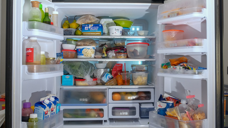 a messy fridge with food and containers