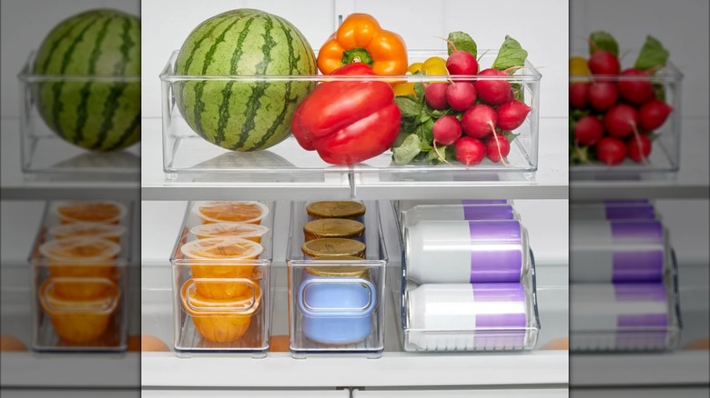 Bins in a fridge filled with fruits, vegetables, soda cans, and food containers