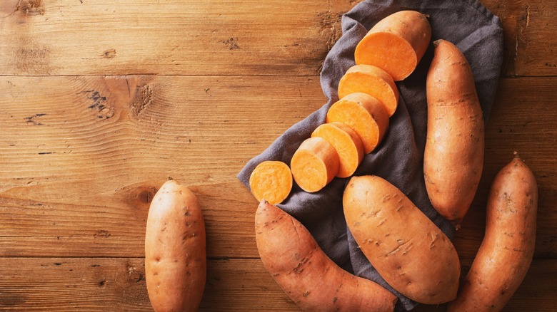 Whole and sliced sweet potatoes on a table
