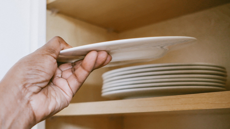 Someone picking up a plate from a stack of white plates