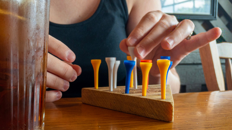 Hands move a peg on a Cracker Barrel peg game